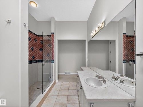Spacious bathroom featuring a glass-enclosed shower with patterned tile, dual vanity with integrated sinks, and ample counter space - 569 Butterworth Way, Edmonton, AB - Indoor Photo Showing Bathroom
