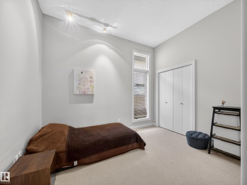 Carpeted room featuring a tall window, bi-fold closet doors, track lighting, and neutral wall tones - 569 Butterworth Way, Edmonton, AB - Indoor Photo Showing Bedroom