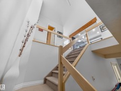 Multi-level staircase featuring light wood railings, clear glass panels, and carpeted treads - 