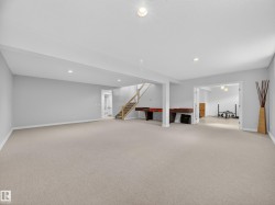 Carpeted open-concept lower level with recessed lighting and light gray wall paint - 