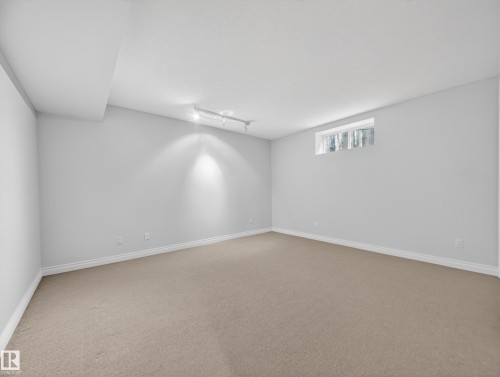 Spacious room featuring neutral carpeting, light-toned walls, and a track lighting fixture - 569 Butterworth Way, Edmonton, AB - Indoor Photo Showing Other Room
