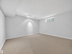 Spacious room featuring neutral carpeting, light-toned walls, and a track lighting fixture - 