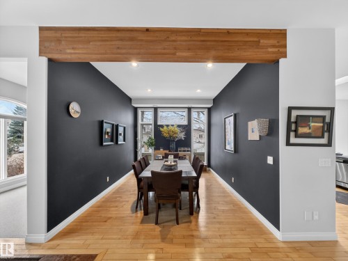 Dining area featuring wood-finish flooring, a prominent decorative wood beam, recessed lighting, and a wall of multi-pane windows - 569 Butterworth Way, Edmonton, AB - Indoor Photo Showing Dining Room