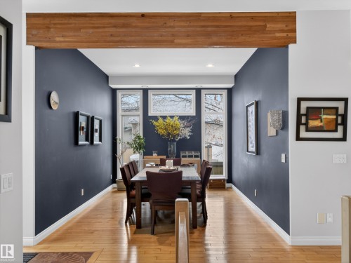 Dining area featuring dark accent walls, wood-finish flooring, a decorative wood beam, and multiple windows - 569 Butterworth Way, Edmonton, AB - Indoor Photo Showing Dining Room
