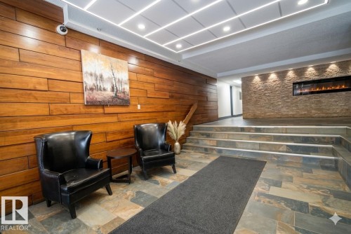 Lobby featuring natural wood paneling, slate tile flooring, an integrated electric fireplace, and recessed lighting - 90 8745 165 Street, Edmonton, AB - Indoor Photo Showing Other Room