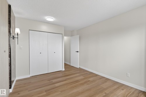 Spacious room featuring wood-finish flooring, white walls, and a ceiling-mounted light fixture - 90 8745 165 Street, Edmonton, AB - Indoor Photo Showing Other Room