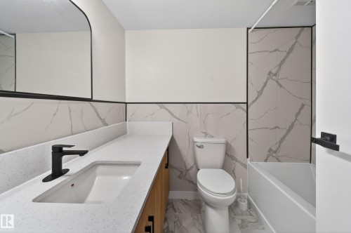 Contemporary bathroom featuring a light-toned vanity with an integrated sink and matte black faucet - 90 8745 165 Street, Edmonton, AB - Indoor Photo Showing Bathroom