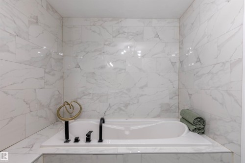 Air-jet bathtub delivers thousands of warm, gentle air bubbles that rise through the water for a soothing, full-body spa experience. Built-in handheld showerhead adds convenience for rinsing, washing, and targeted comfort. - 303 20 Grange Drive, St. Albert, AB - Indoor Photo Showing Bathroom