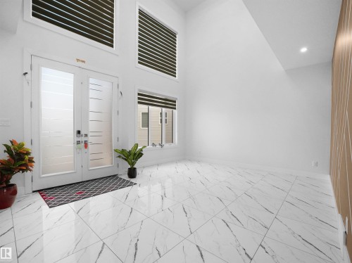Grand entry featuring double doors with frosted glass panels, soaring ceiling height, recessed lighting, and large format marble-look tile flooring - 1208 25 St Nw, Edmonton, AB - Indoor Photo Showing Other Room
