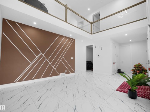 Two-story living area featuring a decorative accent wall with geometric white lines, a second-story open-concept hallway with glass panel railing, recessed ceiling lighting, and large format marble-look tile flooring - 1208 25 St Nw, Edmonton, AB - Indoor Photo Showing Other Room