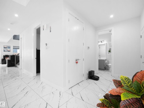 Hallway featuring large format white tile flooring with grey veining, recessed lighting, and crisp white walls - 1208 25 St Nw, Edmonton, AB - Indoor Photo Showing Other Room
