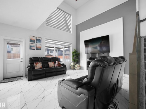 Living area featuring high ceilings, large format tile flooring, a contemporary fireplace facade, and a custom window treatment - 1208 25 St Nw, Edmonton, AB - Indoor Photo Showing Living Room