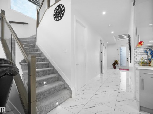 Staircase with glass railing, carpeted treads, and integrated step lighting - 1208 25 St Nw, Edmonton, AB - Indoor Photo Showing Other Room
