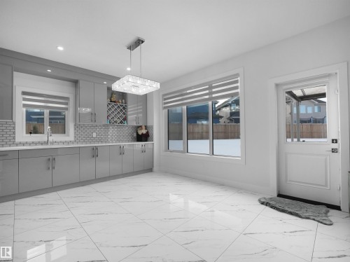 Contemporary kitchen space featuring extensive light grey cabinetry with high-gloss finish, a white subway tile backsplash, and a built-in wine rack - 1208 25 St Nw, Edmonton, AB - Indoor Photo Showing Kitchen