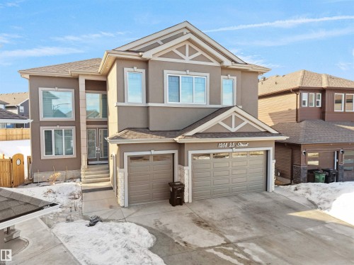 Contemporary two-story residence with a stucco exterior, featuring a double attached garage and stone accents - 1208 25 St Nw, Edmonton, AB - Outdoor With Facade
