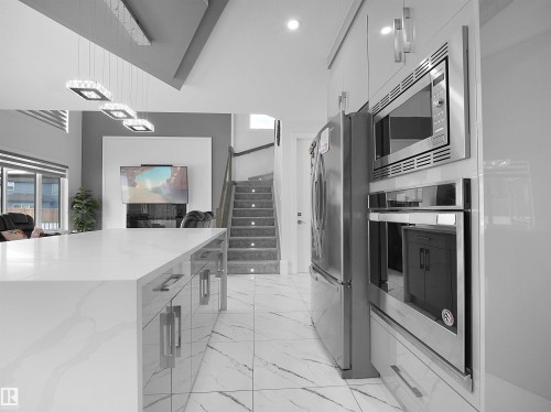 Kitchen island with a quartz countertop and high-gloss cabinetry - 1208 25 St Nw, Edmonton, AB - Indoor Photo Showing Kitchen With Upgraded Kitchen