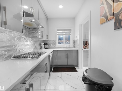 Galley kitchen featuring a gas cooktop, sleek grey cabinetry, white countertops, and a subway tile backsplash - 1208 25 St Nw, Edmonton, AB - Indoor Photo Showing Kitchen With Upgraded Kitchen