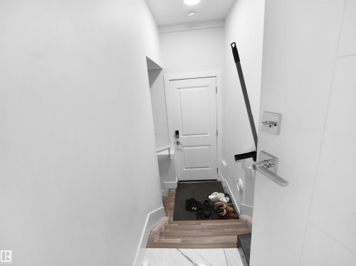 Entryway featuring a white paneled door, wood-finish stairs, and contemporary door hardware - 1208 25 St Nw, Edmonton, AB - Indoor Photo Showing Other Room