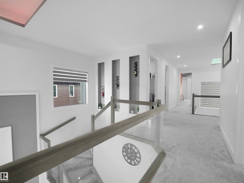 Upper-level hallway with plush carpet flooring, recessed lighting, and a glass-paneled railing - 1208 25 St Nw, Edmonton, AB - Indoor Photo Showing Other Room