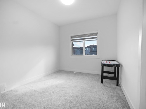 Neutral interior room featuring light gray carpet flooring, white walls, white trim, and a single window with blinds - 1208 25 St Nw, Edmonton, AB - Indoor Photo Showing Other Room