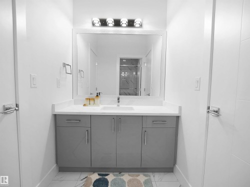 Modern vanity featuring a light gray base with contemporary hardware, a white countertop, and an integrated sink - 1208 25 St Nw, Edmonton, AB - Indoor Photo Showing Bathroom