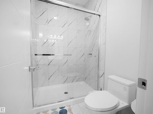 Contemporary shower enclosure with clear glass doors, white tiled walls featuring gray veining, and a white shower pan - 1208 25 St Nw, Edmonton, AB - Indoor Photo Showing Bathroom