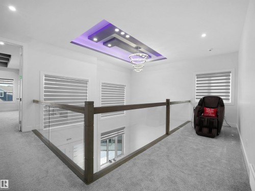 Upper-level landing featuring a custom tray ceiling with recessed lighting and a contemporary multi-ring chandelier - 1208 25 St Nw, Edmonton, AB - Indoor Photo Showing Other Room
