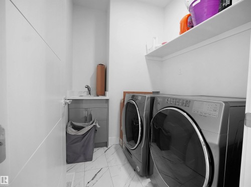 Dedicated laundry area featuring a utility sink with a quartz-finish countertop and gray cabinetry - 1208 25 St Nw, Edmonton, AB - Indoor Photo Showing Laundry Room