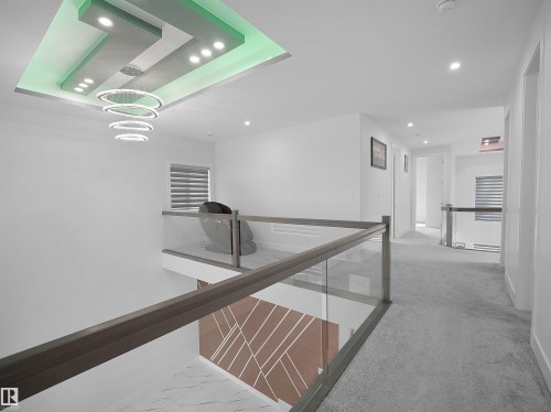 Recessed and cove lighting illuminates a tiered ceiling design, complementing the modern chandelier - 1208 25 St Nw, Edmonton, AB - Indoor Photo Showing Other Room