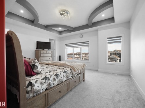Spacious room featuring a decorative tray ceiling with recessed lighting and a central chandelier - 1208 25 St Nw, Edmonton, AB - Indoor Photo Showing Bedroom