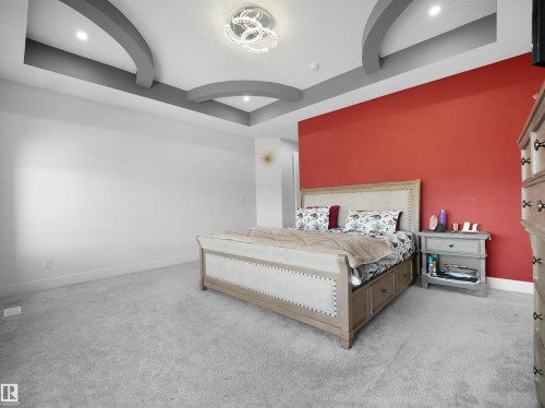 Bedroom featuring a striking red accent wall and light gray carpeting - 1208 25 St Nw, Edmonton, AB - Indoor Photo Showing Bedroom
