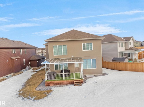 Rear exterior featuring a covered deck with a clear panel roof, brown painted siding, and multiple windows - 1208 25 St Nw, Edmonton, AB - Outdoor