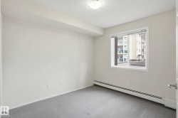 Neutral-toned room featuring a large window, carpet flooring, baseboard heating, and ceiling lighting - 