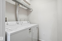 Dedicated laundry area featuring a white top-load washer and dryer set, overhead wire shelving, and neutral wall finishes - 