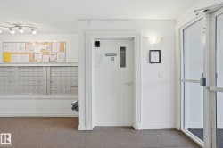 Community entrance featuring secure mailboxes, track lighting, and a glass-paneled entry door - 