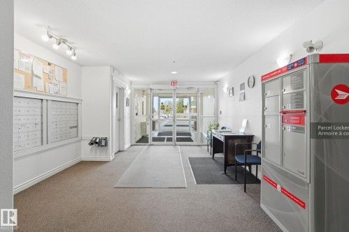 Entry foyer with glass double doors, wall-mounted mailboxes, parcel locker system, and track lighting - 120 13625 34 Street, Edmonton, AB - Indoor Photo Showing Other Room