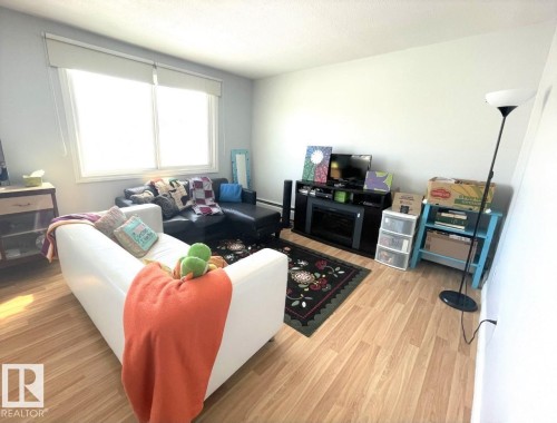 Living area with wood-finish flooring, light-colored walls, and a large window - 303 12223 82 Street, Edmonton, AB - Indoor Photo Showing Living Room