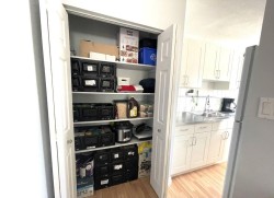 Kitchen pantry with bi-fold doors offering multiple shelves for storage - 