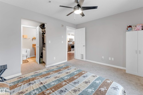 Carpeted room with a ceiling fan, light gray painted walls, and white trim - 201 4403 23 Street, Edmonton, AB - Indoor Photo Showing Bedroom