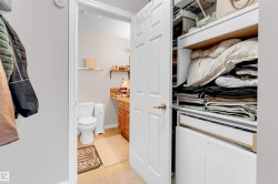 Compact water closet featuring a vanity with a light wood-finish cabinet, a white countertop, and a tiled backsplash - 
