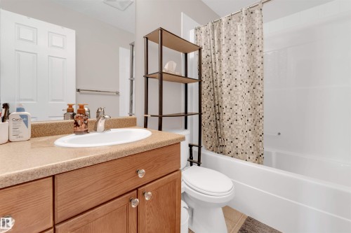 Vanity featuring an integrated sink, laminate countertop, and wood-finish cabinetry with clear knob hardware - 201 4403 23 Street, Edmonton, AB - Indoor Photo Showing Bathroom