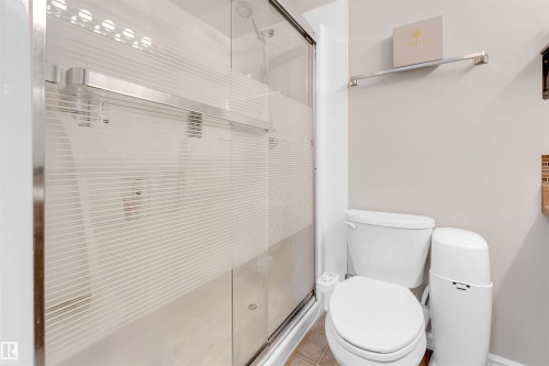 Shower enclosure with frosted glass panels, chrome hardware, and a white tile surround - 201 4403 23 Street, Edmonton, AB - Indoor Photo Showing Bathroom