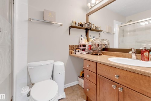 Bathroom featuring a light wood-finish vanity with an integrated sink, a large mirror, and tiled flooring - 201 4403 23 Street, Edmonton, AB - Indoor Photo Showing Bathroom