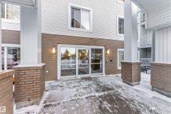 Building exterior featuring a glass entry, brick facade, white siding, and outdoor sconce lighting - 
