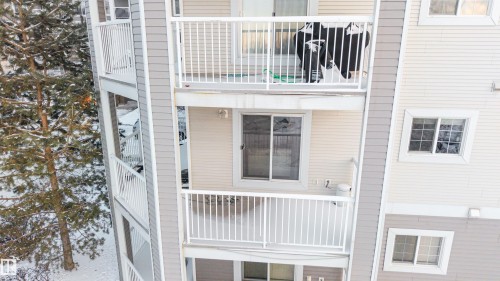 Multi-level residential building featuring light-colored horizontal siding and white balconies with vertical railings - 201 4403 23 Street, Edmonton, AB - Outdoor With Exterior