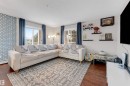 Spacious living area featuring wood-finish flooring, a geometric accent wall, and multiple windows providing ample natural light - 201 4403 23 Street, Edmonton, AB  - Indoor Photo Showing Living Room 