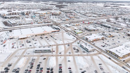 Aerial perspective showcasing a commercial district with multiple retail establishments, extensive parking areas, and surrounding residential neighborhoods - 201 4403 23 Street, Edmonton, AB -  With View