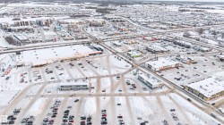 Aerial perspective showcasing a commercial district with multiple retail establishments, extensive parking areas, and surrounding residential neighborhoods - 