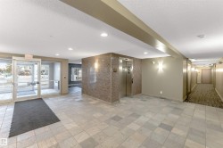 Spacious entrance lobby featuring large format tile flooring, a textured accent wall, stainless steel elevator, recessed lighting, and glass entry doors - 