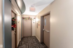 Hallway featuring patterned carpet flooring, neutral wall paint, and wall-mounted sconce lighting - 